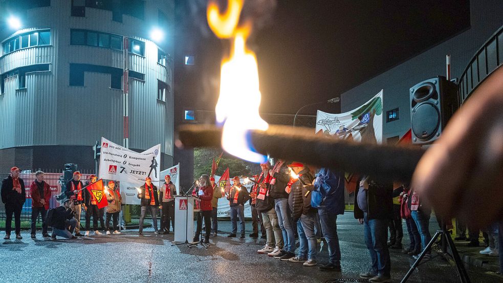 Mitarbeiter von Volkswagen standen am Dienstag mit Fackeln vor dem VW Werk in Osnabrück. Dieses Werk gilt als schließungsgefährdet. Am Mittwoch war dann aber plötzlich auch von Emden die Rede. Foto: Guido Kirchner/DPA