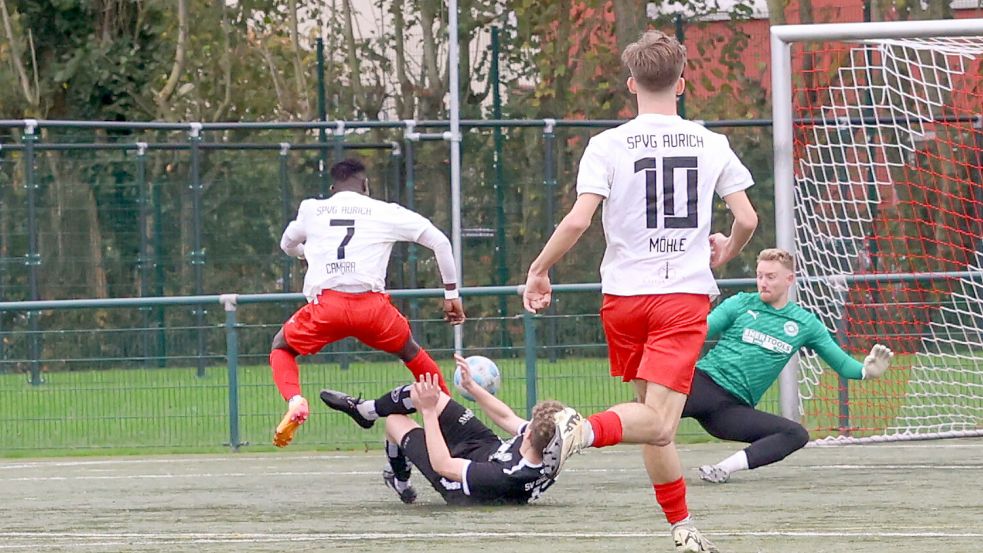 Wie ein Hürdenläufer überspringt der Auricher Moustapha Camara (links) einen Fehntjer Abwehrspieler und schiebt nach seiner akrobatischen Einlage den Ball vorbei an SVG-Torhüter Timo Kuhlmann (rechts) zum 1:0 für die SpVg Aurich. Nico Möhle schaut sich die gelungenen Aktion an. Foto: Helmut Vortanz