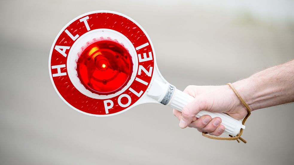 Ein Polizist hält eine Kelle in der Hand. Foto: DPA