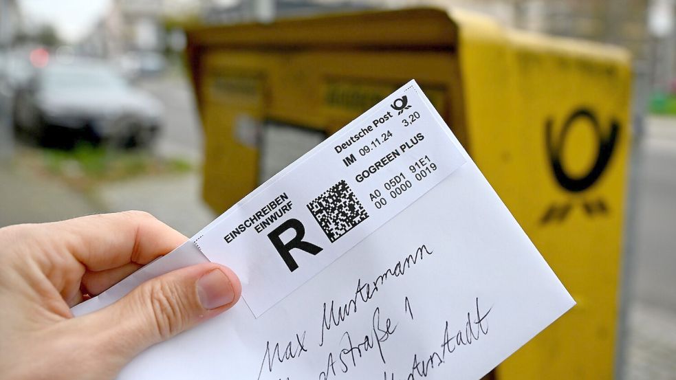 Ein Mann hält ein sogenanntes Einwurf-Einschreiben vor einen Briefkasten (gestellte Szene). Foto: Wolf von Dewitz/dpa