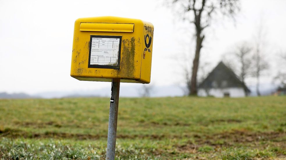 Ein Briefkasten der Deutschen Post steht auf einer Wiese am Rand einer Siedlung im Bergischen Land (NRW). Foto: Oliver Berg/dpa