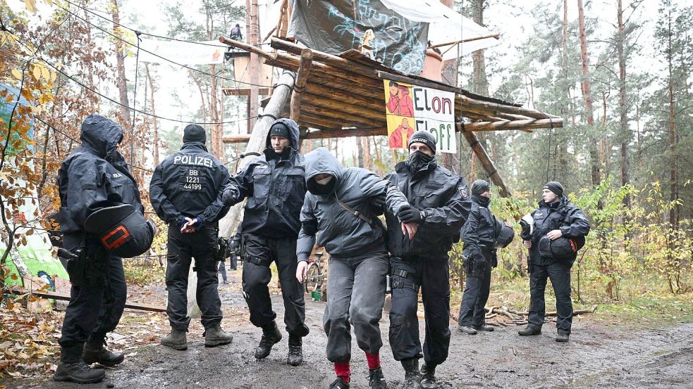 Ein Aktivist wird von Polizisten aus dem Protestcamp in der Nähe des Tesla-Autowerks in Grünheide abgeführt. Foto: Sebastian Christoph Gollnow/dpa