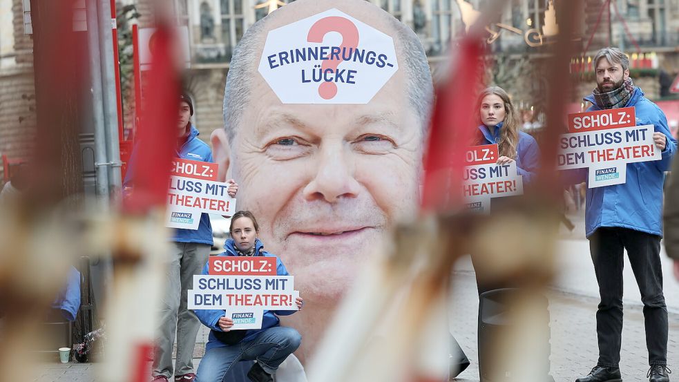 Bei einer Protestaktion der Bürgerbewegung Finanzwende halten die Demonstrierenden ein Plakat mit dem Porträt von Bundeskanzler Olaf Scholz und dem Wort „Erinnerungslücke?“ auf seiner Stirn. Foto: picture alliance/dpa