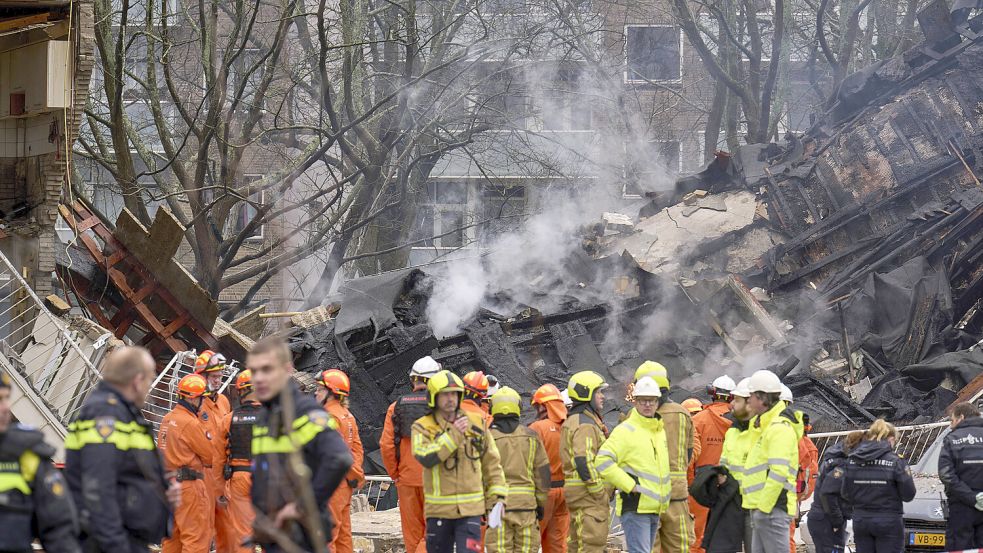 Feuerwehrleute stehen vor dem zerstörten Gebäude am Ort der Explosion in Den Haag, bei der mehrere Wohnungen zerstört wurden und sechs Menschen ums Leben gekommen sind. Foto: dpa/Phil Nijhuis