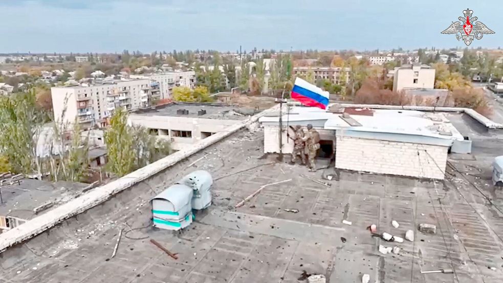 Russische Soldaten hissen in einer Ortschaft auf einem Gebäude eine Fahne nach dessen Einnahme. (Archivbild/Handout) Foto: Uncredited/Russian Defense Ministry Press Service/AP/dpa