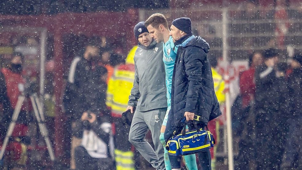 Folge des Feuerzeugwurfs: Torwart Patrick Drewes wird vom Platz geführt. Foto: Andreas Gora/dpa