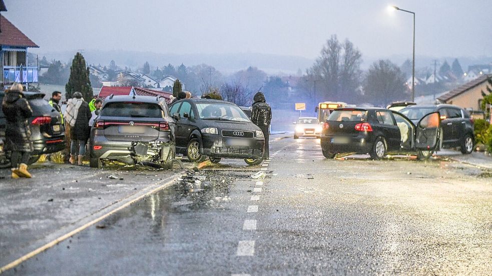 Nach einem Unfall bei Glatteis mit mehreren Fahrzeugen in Baden-Württemberg stehen Helfer und Beteiligte an den Autos auf einer Straße. Foto: Jason Tschepljakow/dpa