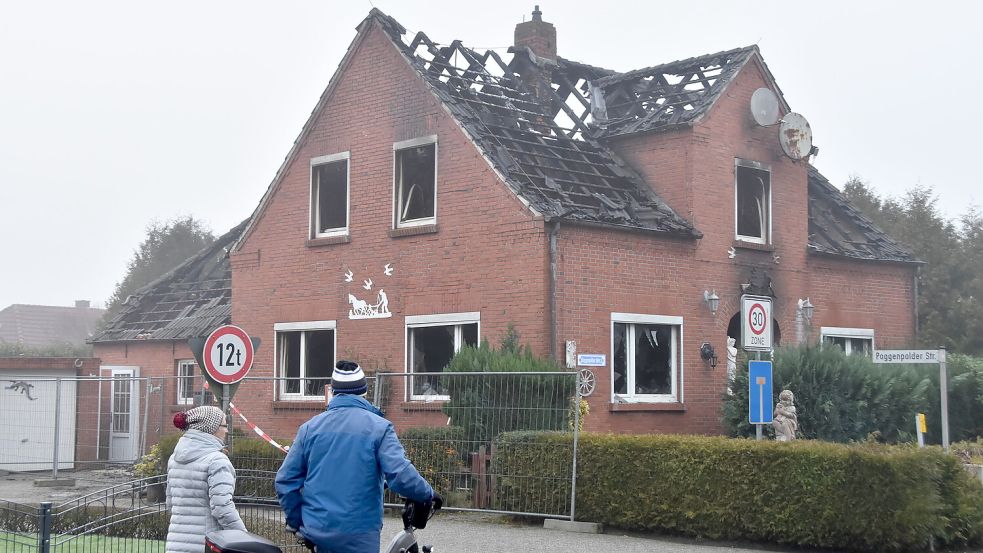 Passanten betrachten am Tag nach dem Feuer die Brandruine in Upgant-Schott. Foto: Thomas Dirks