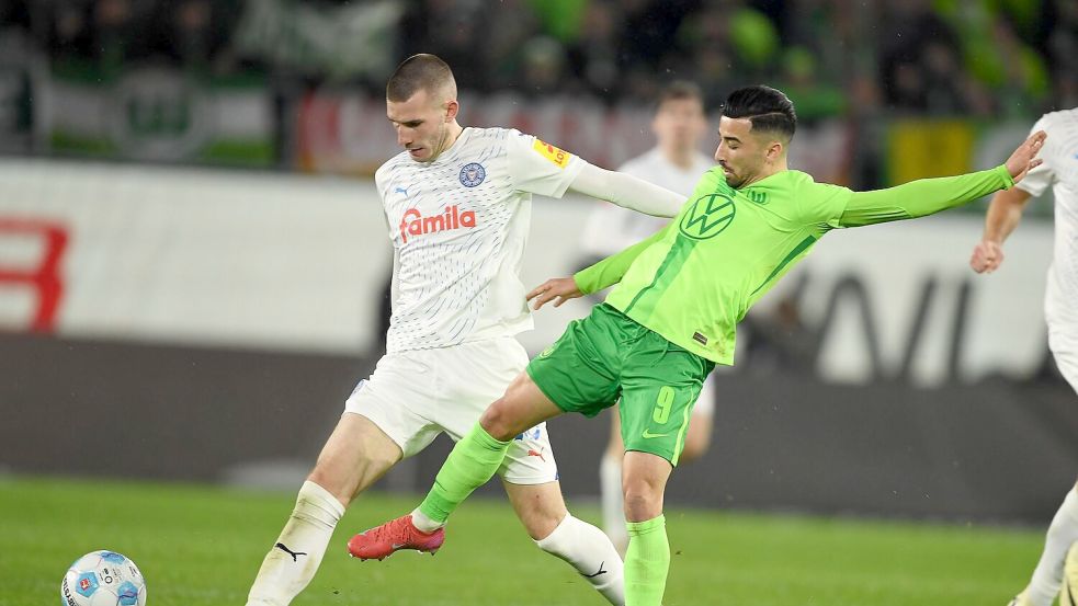 Wolfsburgs Mohamed Amoura (r) spielt gegen Kiels David Zec. Foto: Swen Pförtner/dpa