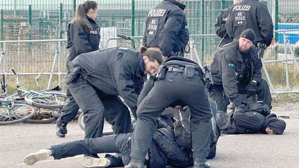 Polizisten halten Demonstranten am Boden fest. Sie hatten zuvor versucht mit Fahrrädern Richtung Veranstaltungshalle vorzudringen. Foto: Jörg Ratzsch/dpa