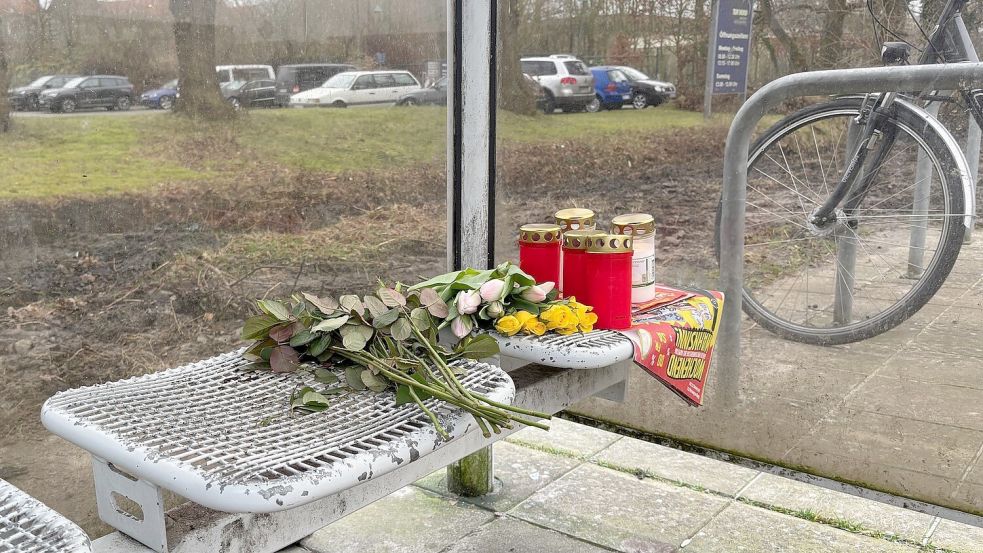 Blumen und Kerzen erinnern zwei Tage nach dem Fund der Leiche an die obdachlose Frau, die über Monate in dem Buswartehäuschen lebte. Foto: Mieke Matthes