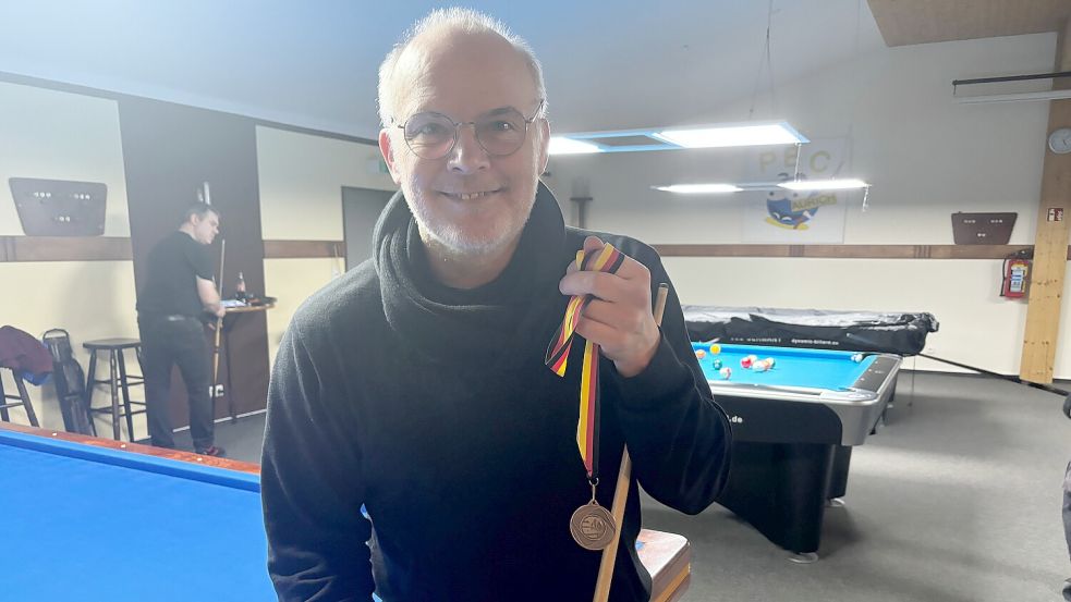 Stolz präsentiert Ralf Bolduan seine Bronzemedaille. Im Hintergrund des Vereinsheims in Plaggenburg sind die neuen Billardtische zu sehen. Foto: Marco Lindenbeck