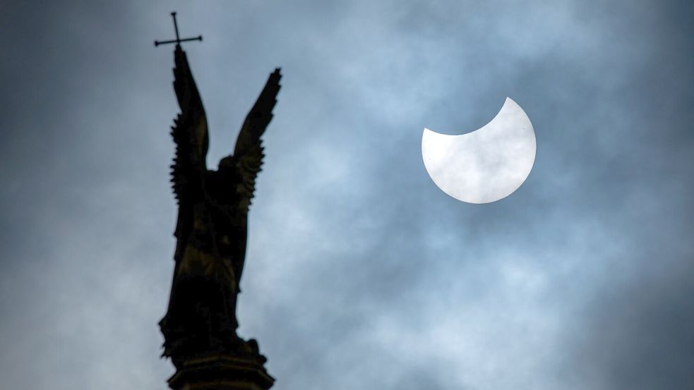 Eine partielle Sonnenfinsternis über der Statue des Erzengel Michael auf der Kuppel des Schweriner Schlosses. Foto: Jens Büttner/dpa