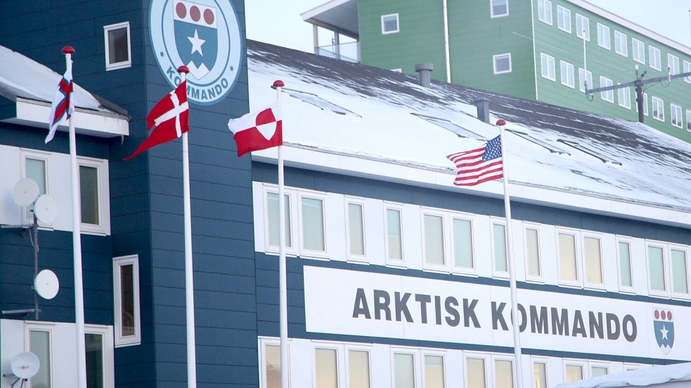 Die Flaggen von Dänemark und Grönland wehen vor dem Hauptquartier des Arktischen Kommandos neben einer US-Flagge. In dem Gebäude befindet sich auch das Konsulat der USA in Grönland. Am 11.03.2025 haben die Grönländer die Wahl. Foto: DPA/Steffen Trumpf